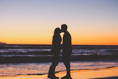 Man and woman kissing on beach at sunset
